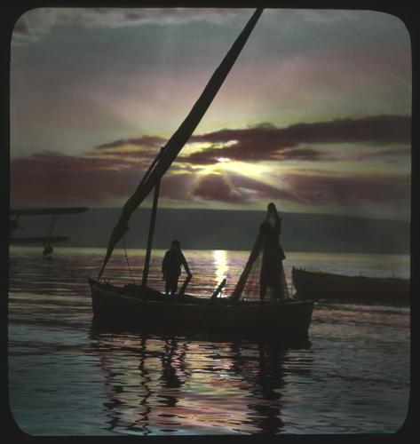 Lake Gililee. Fisherman. Rowing fishing boat with furled sail at sunrise.